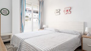 A bedroom with a bed, a nightstand, a wall with a puzzle piece saying 'ME,' and a window with curtains.