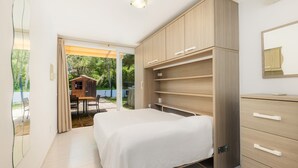 Un dormitorio con cama, armario de madera y vistas a un patio exterior.