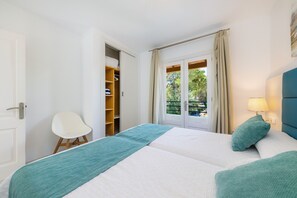 Quarto com cama, cadeira, guarda-roupa e janela com cortinas.