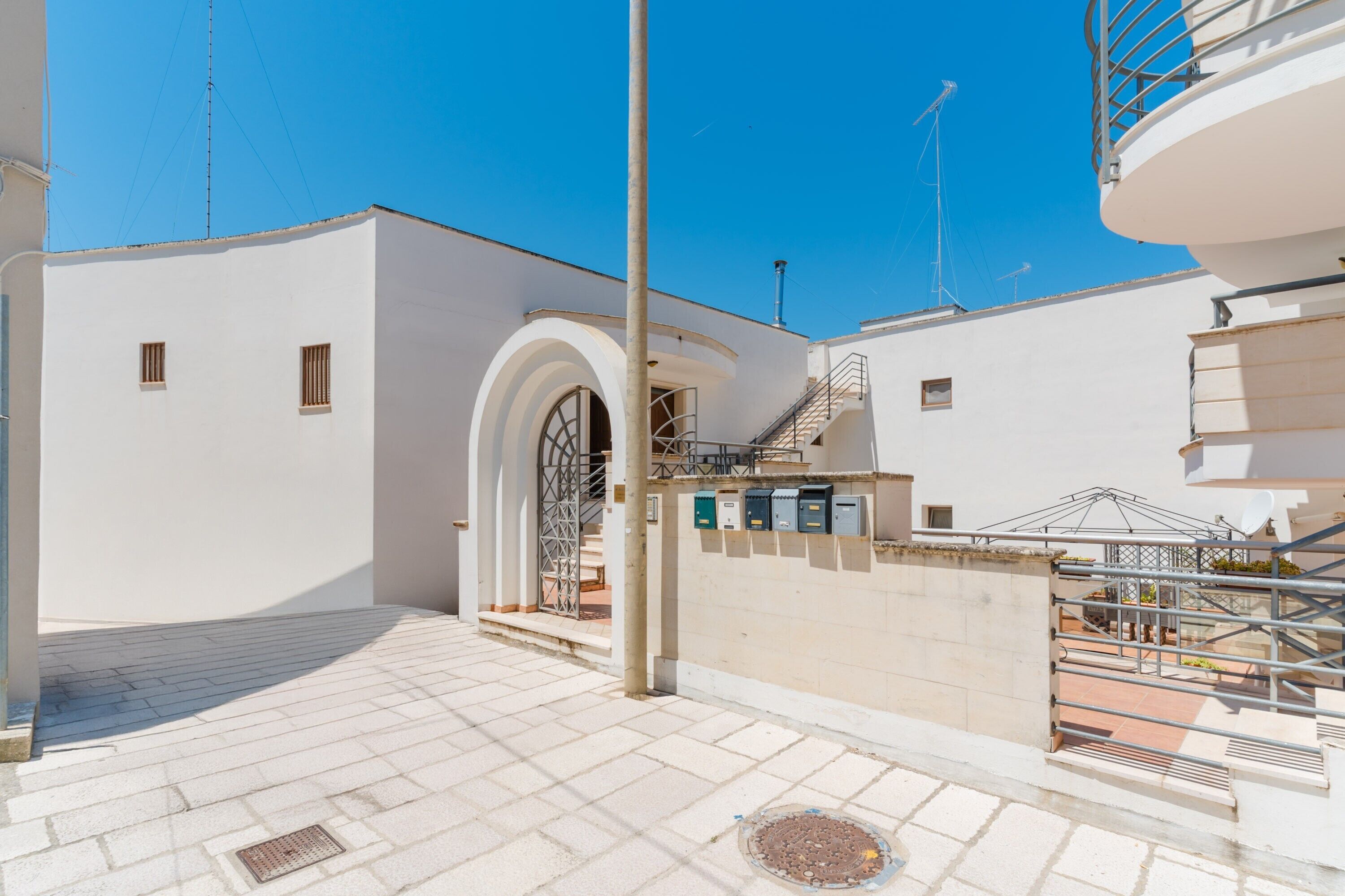 A building with a white exterior, a metal gate, and a staircase leading to an upper level.