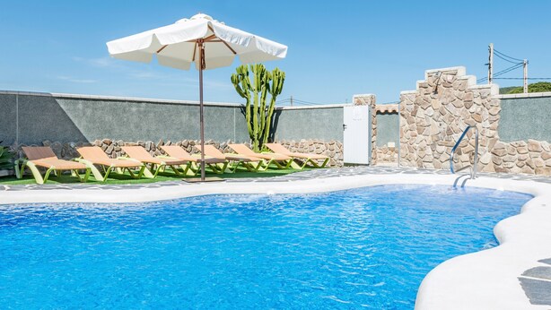 A swimming pool with lounge chairs and a cactus, surrounded by stone walls. - Air-Conditioned Apartment Close to the Beach with Pool, Terrace, Garden & Wi-Fi (Zahora)