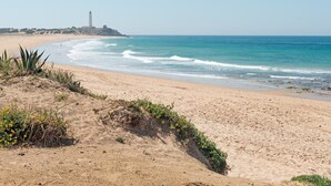 A beach with a lighthouse, sandy dunes, and ocean waves. - Air-Conditioned Apartment Close to the Beach with Pool, Terrace, Garden & Wi-Fi (Zahora)