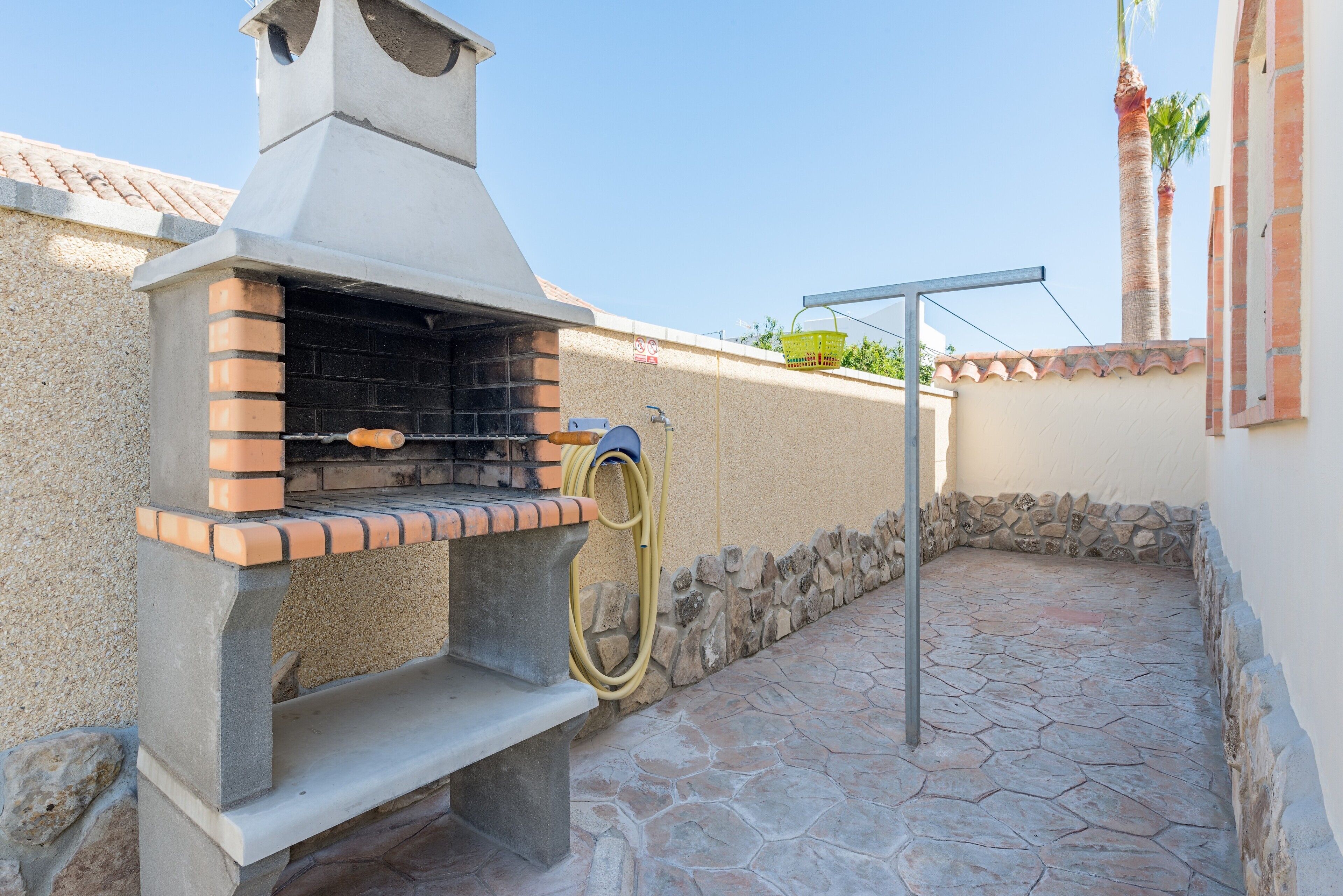 Una parrilla para barbacoa con una chimenea, una manguera y un muro de piedra.