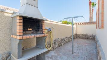 Una parrilla para barbacoa con una chimenea, una manguera y un muro de piedra.
