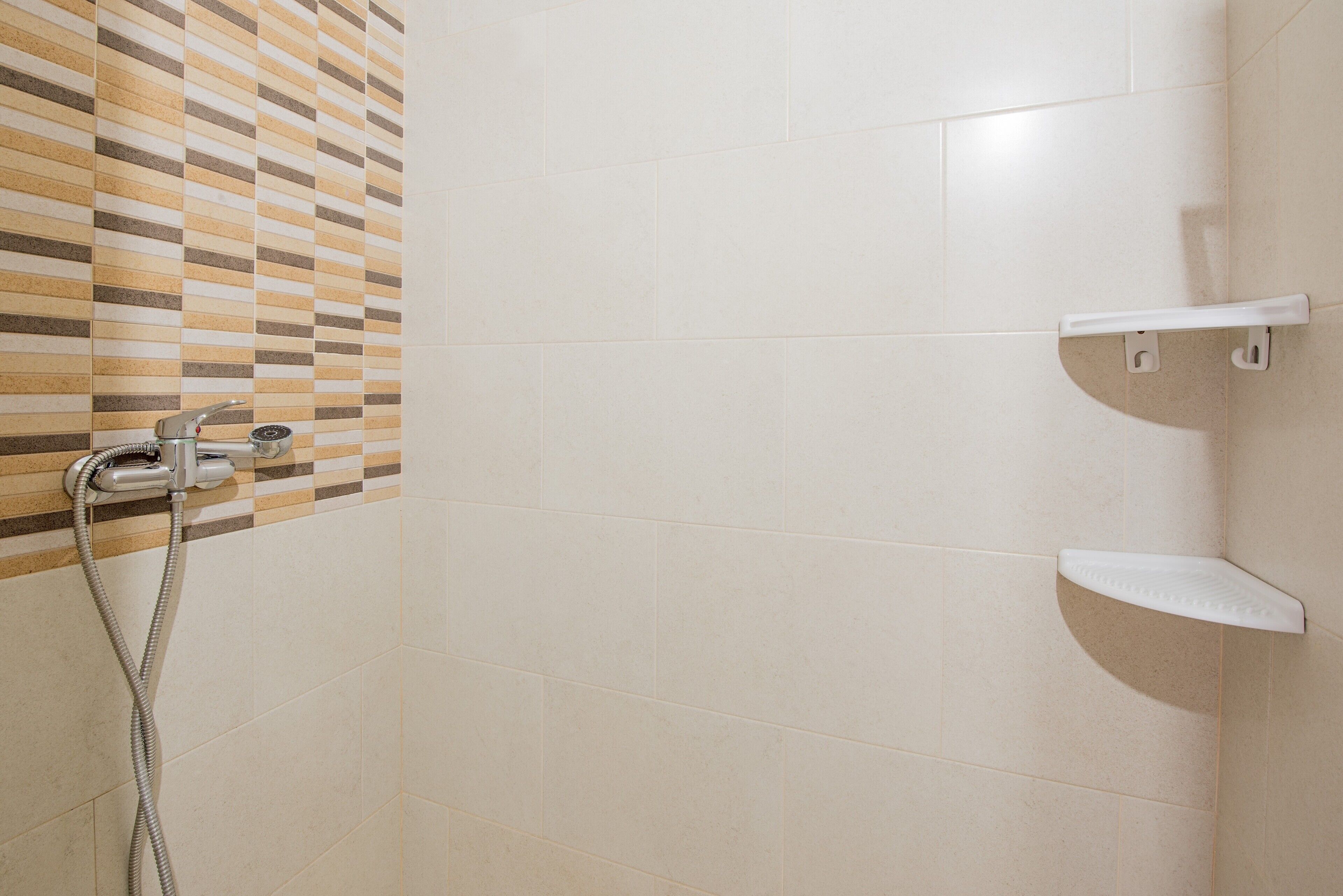 Zona de ducha con pared de azulejos, ducha y un perchero para toallas.