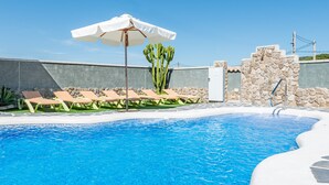Ein Swimmingpool mit Liegestühlen und einer Kaktee.