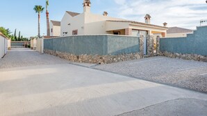 Ein Wohnhaus mit befestigter Auffahrt, Steinmauer und einem Dach mit Schornsteinen.