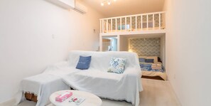 A compact room with a white sofa, a small round table, and a bunk bed with a patterned headboard. - WARAYUN SO Port city May (Naha)