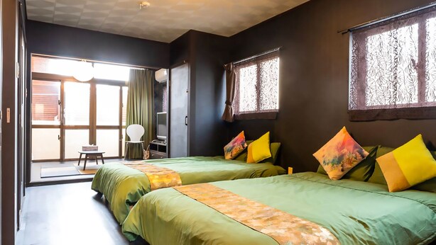 Una habitación con dos camas, una silla y una puerta corredera que da a un espacio al aire libre.
