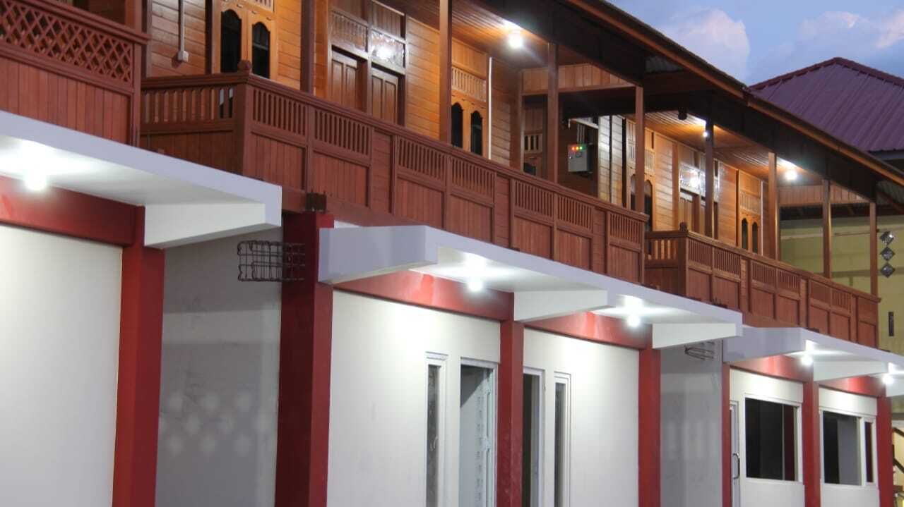 Et hotel med en traditionel træfacade, flere altaner og en række værelser med hvide vægge og røde detaljer.
