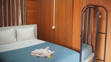 Quarto com cama, cabeceira de madeira, escada de metal e colcha azul.