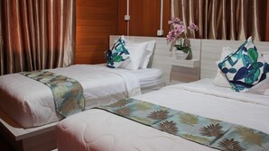 Une chambre d’hôtel avec deux lits, des lambris en bois sur les murs et une petite table sur laquelle est posé un vase de fleurs.