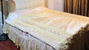 A bedroom with a large bed, a nightstand, a lamp, and a window with curtains. - Dot King Villa (Taipei)