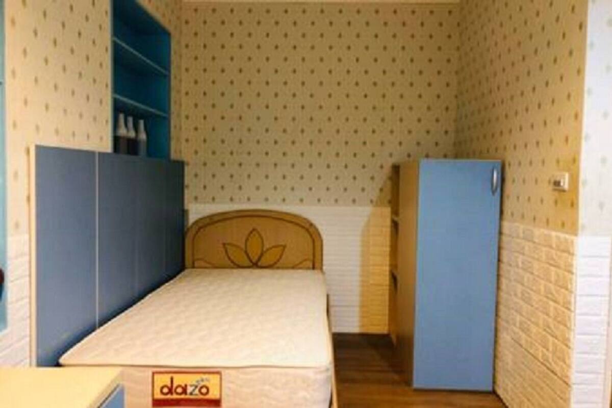 A small, compact room with a single bed, a wardrobe, and a small cabinet.