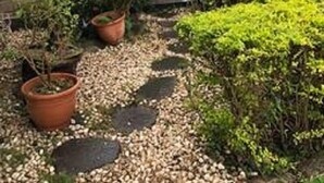 A garden with potted plants, a stone pathway, and a wooden pergola. - Dot King Villa (Taipei)