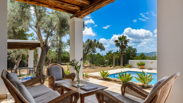An outdoor patio with wicker furniture, a pool, and a view of trees and hills. - Air-conditioned Villa with Pool, Terrace and Wi-Fi (Sant Joan de Labritja)
