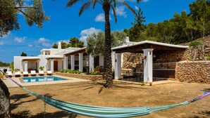 A modern villa with a swimming pool, outdoor seating, and a stone wall. - Air-conditioned Villa with Pool, Terrace and Wi-Fi (Sant Joan de Labritja)