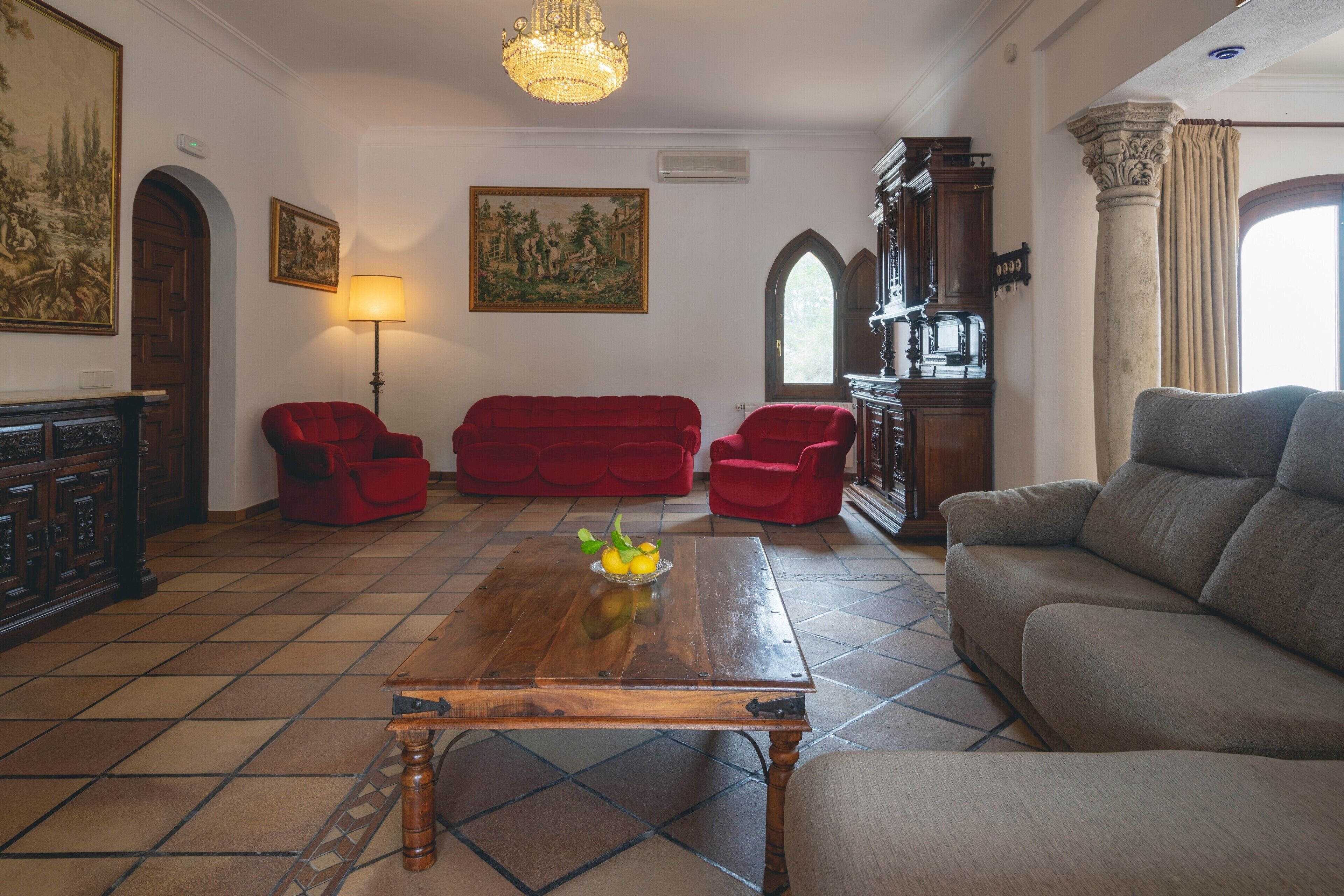 A living room with a wooden coffee table, red sofas, and a grey sofa.