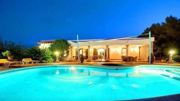 A swimming pool with lounge chairs, a covered patio area, and a building with arches. - Beautiful Holiday Home with Mountain View, Pool, Wi-Fi, Garden and Air Conditioning (Santa Eulalia del Río)