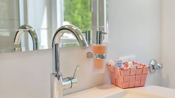 A bathroom with a modern faucet, a soap dispenser, and a basket of toiletries.