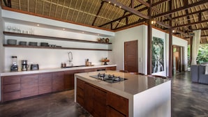A modern kitchen with a large island, wooden cabinets, and a high ceiling with exposed beams.