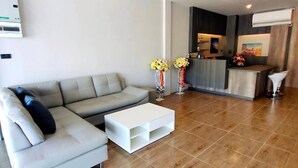 Een moderne woonkamer met een grijze modulaire bank, een witte salontafel en een keuken in de achtergrond.