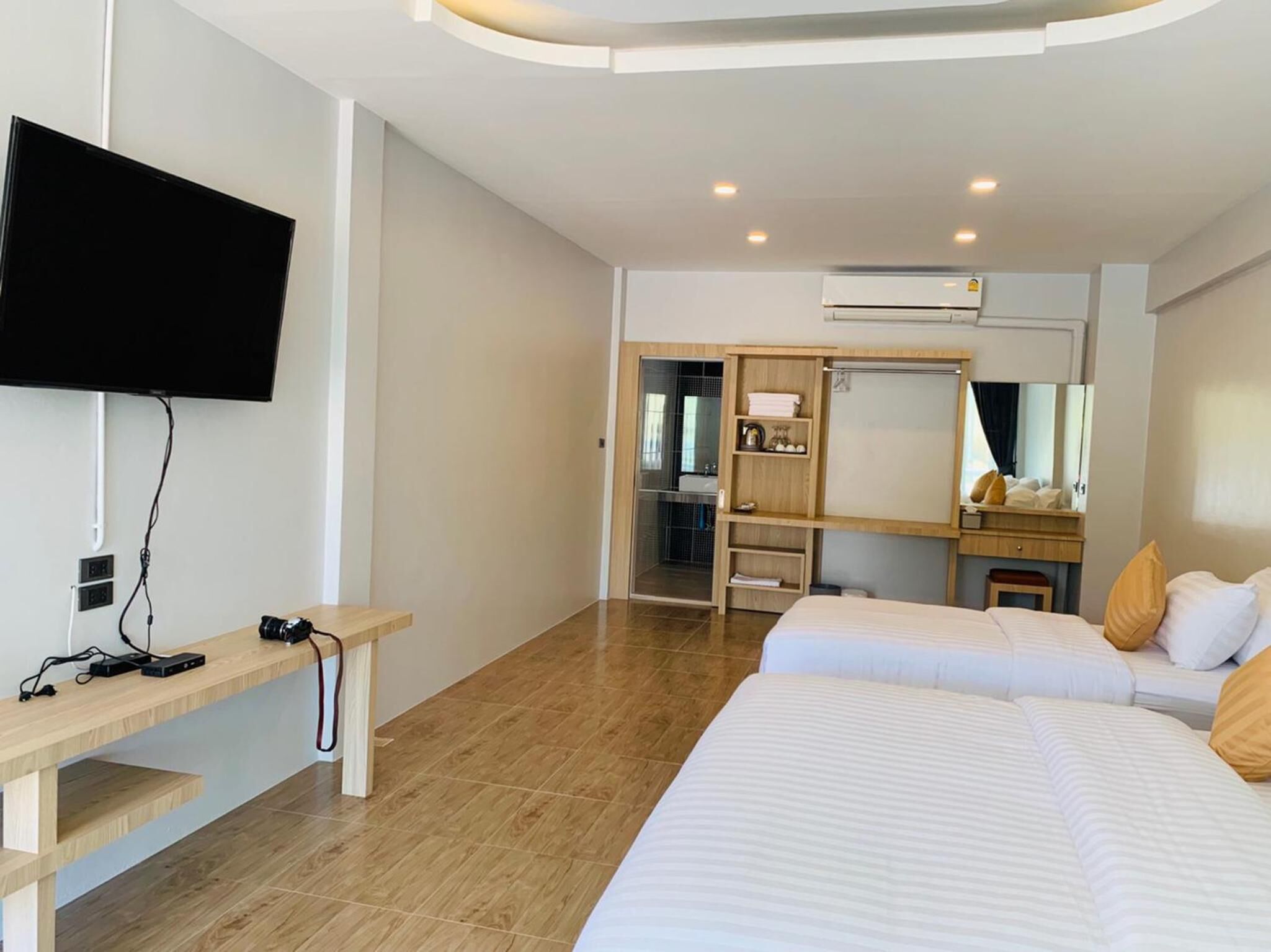 A hotel room with a bed, bedside table, TV, and a desk with a chair.
