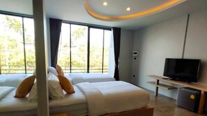 Een moderne slaapkamer met een groot bed, een televisie en een kleine koelkast.