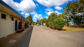 A street view with a building labeled "MANGOLITE" on the left, a clear sky, and trees on the right.