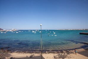 Une plage avec une eau claire, des bateaux et un lampadaire.