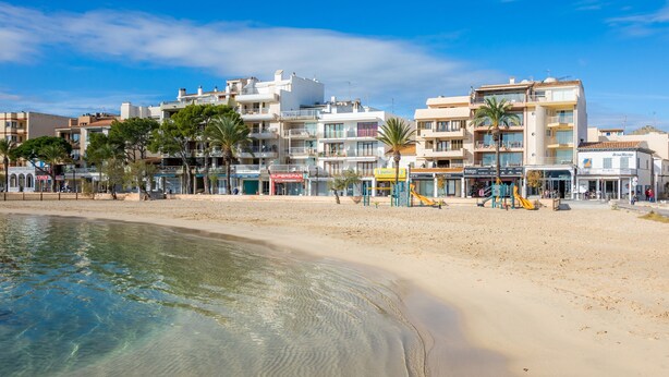 Ein Hotel direkt am Strand mit mehreren Etagen, einem Sandstrand und Palmen.