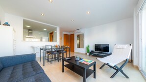 Ein modernes Wohnzimmer mit einer Couch, einem Couchtisch, einem Fernseher und einem Sessel.