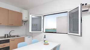 A compact kitchen with a window, a table, chairs, and a water heater.