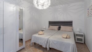A bedroom with a bed, bedside tables, a wardrobe, and a unique ceiling light fixture.