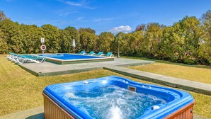 A hot tub and a swimming pool with lounge chairs, surrounded by trees. - Country House 'Sa Pova' with Mountain View, Wi-Fi and Air Conditioning (Alcúdia)