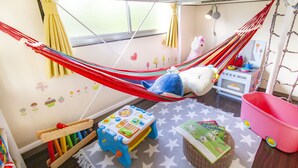 A child's playroom with a hammock, toys, and a star-patterned rug. - Espoir Omorimachi (Tokyo)