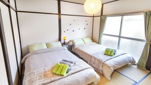 A hotel room with two beds, a small table with a lamp, and a wall with circular decorations. - Espoir Omorimachi (Tokyo)