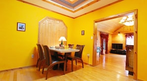A dining area with a wooden table and chairs, a lamp, and a wooden door leading to another room.