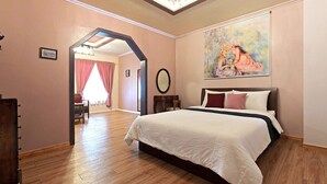 A bedroom with a large bed, a painting on the wall, and a wooden floor. - Gyeongju Europe Village Pension (Gyeongju)