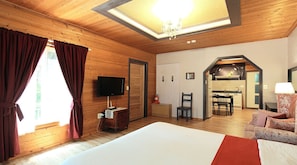 A hotel room with a large bed, wooden walls, a TV, a desk, and a chair. - Gyeongju Europe Village Pension (Gyeongju)