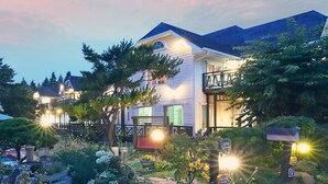 A well-lit residential area with a swimming pool, surrounded by lush greenery and houses with visible balconies. - Gyeongju Europe Village Pension (Gyeongju)