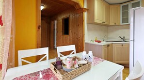 A cozy kitchen with wooden cabinets, a white refrigerator, and a dining area with a table set for two. - Gyeongju Europe Village Pension (Gyeongju)