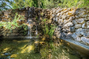 A stone wall with a small waterfall and a pond.