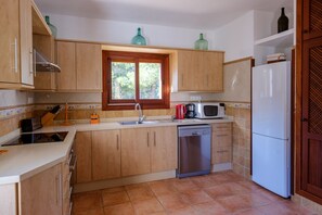 Una cocina con armarios de madera, lavavajillas, microondas y refrigerador.