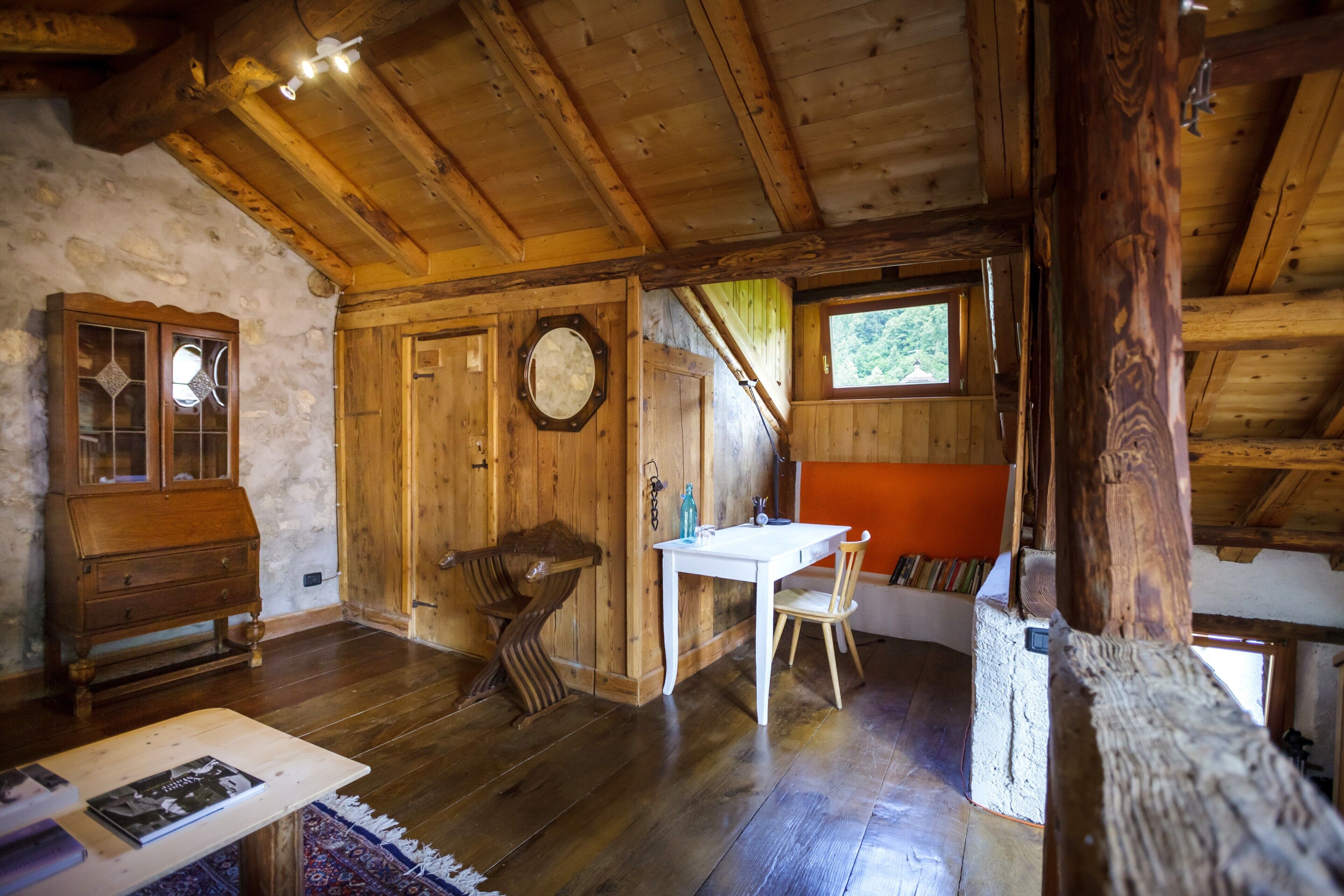 A rustic wooden interior with a wooden table, a chair, a dresser, and a window.