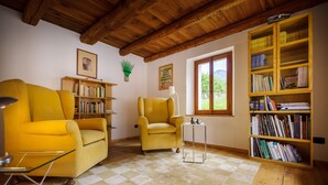 A room with a checkered carpet, two yellow armchairs, a bookshelf, and a window with a view.