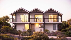 A modern two-story house with large windows and a balcony.