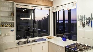 A modern kitchen with two large windows, a built-in oven, and a knife rack.