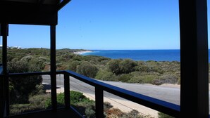 A balcony with a view of the sea and a road.