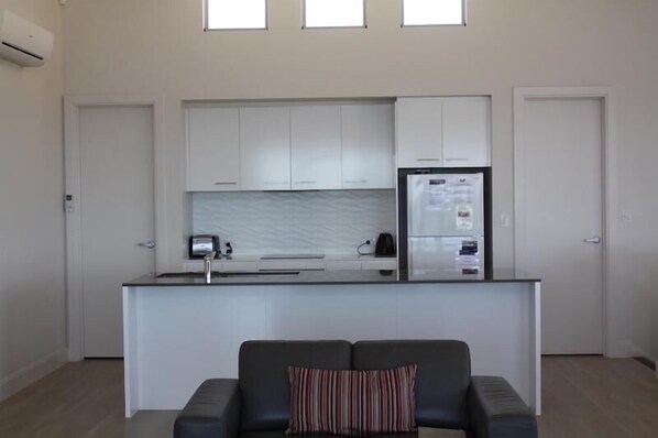 A compact kitchen with white cabinets, a built-in refrigerator, and a small island with a sink.